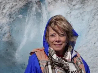 A woman in blue jacket and scarf near water.